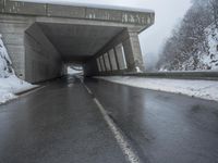 a motorcycle is parked by a tunnel near some snow covered trees outside of the tunnel