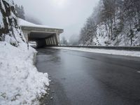 a motorcycle is parked by a tunnel near some snow covered trees outside of the tunnel