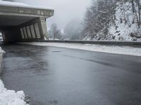 a motorcycle is parked by a tunnel near some snow covered trees outside of the tunnel