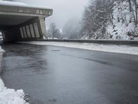a motorcycle is parked by a tunnel near some snow covered trees outside of the tunnel