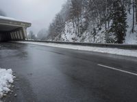 a motorcycle is parked by a tunnel near some snow covered trees outside of the tunnel