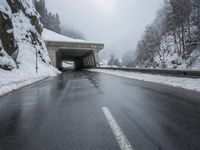 a motorcycle is parked by a tunnel near some snow covered trees outside of the tunnel