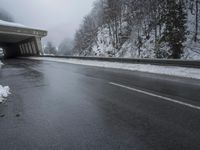a motorcycle is parked by a tunnel near some snow covered trees outside of the tunnel