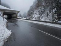 a motorcycle is parked by a tunnel near some snow covered trees outside of the tunnel