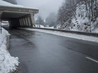 a motorcycle is parked by a tunnel near some snow covered trees outside of the tunnel