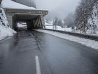 a motorcycle is parked by a tunnel near some snow covered trees outside of the tunnel