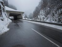 a motorcycle is parked by a tunnel near some snow covered trees outside of the tunnel