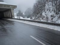 a motorcycle is parked by a tunnel near some snow covered trees outside of the tunnel
