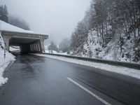 a motorcycle is parked by a tunnel near some snow covered trees outside of the tunnel