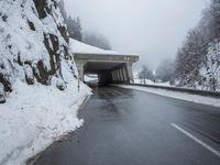 a motorcycle is parked by a tunnel near some snow covered trees outside of the tunnel