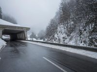 a motorcycle is parked by a tunnel near some snow covered trees outside of the tunnel