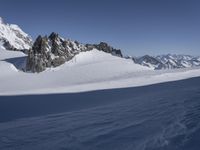 a lone person skis in the snow in front of a mountain peak with a shadow on it