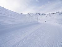 snow covered slope in the middle of a ski area as people ski on it near ski lift