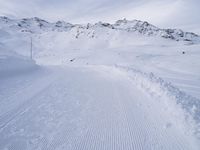 snow covered slope in the middle of a ski area as people ski on it near ski lift