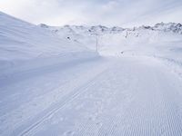 snow covered slope in the middle of a ski area as people ski on it near ski lift