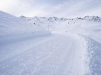 snow covered slope in the middle of a ski area as people ski on it near ski lift