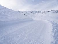 snow covered slope in the middle of a ski area as people ski on it near ski lift