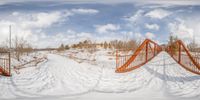 two bridges across snowy field by house in winter scene with orange railings and snow