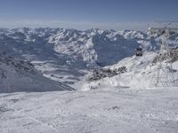 the mountains are covered in snow with a skier coming down a steep mountain side to the bottom