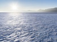 a snow - covered ocean with mountains in the distance and one boat floating near it
