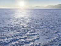 a snow - covered ocean with mountains in the distance and one boat floating near it