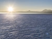 a snow - covered ocean with mountains in the distance and one boat floating near it