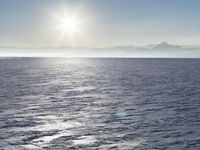 a snow - covered ocean with mountains in the distance and one boat floating near it