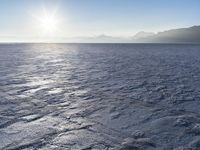 a snow - covered ocean with mountains in the distance and one boat floating near it