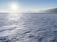 a snow - covered ocean with mountains in the distance and one boat floating near it