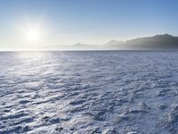 a snow - covered ocean with mountains in the distance and one boat floating near it