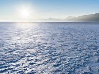 a snow - covered ocean with mountains in the distance and one boat floating near it