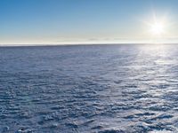 a snow - covered ocean with mountains in the distance and one boat floating near it