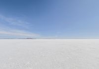 snow covered field with blue sky in the distance of the view is empty and full of snow