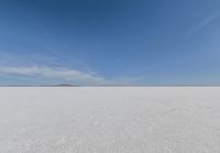 snow covered field with blue sky in the distance of the view is empty and full of snow