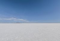 snow covered field with blue sky in the distance of the view is empty and full of snow