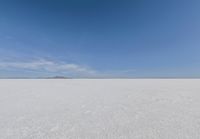 snow covered field with blue sky in the distance of the view is empty and full of snow