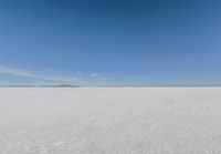 snow covered field with blue sky in the distance of the view is empty and full of snow