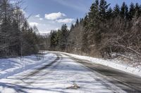 a long road with snow and trees on both sides with sky and clouds above them