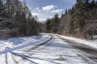 a long road with snow and trees on both sides with sky and clouds above them