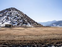 a small stone building on top of a snow covered hill next to a body of water