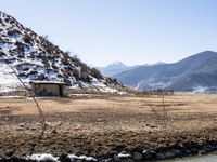 a small stone building on top of a snow covered hill next to a body of water