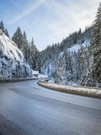 road in the mountains with snow on it and evergreen trees on both sides with sunbeams and blue skies