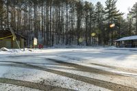 a small building and some trees in the back ground covered in snow and the sun