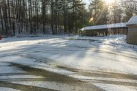 a small building and some trees in the back ground covered in snow and the sun