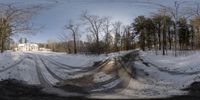 a snow covered road leads up to a house surrounded by trees with a big white house behind it