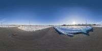 a panorama of the road after snow with no cars on it and the sun shining in the sky