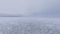 a picture of an overcast sky over a vast plain of snow with a large mountain in the distance