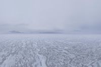 a picture of an overcast sky over a vast plain of snow with a large mountain in the distance