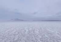 a picture of an overcast sky over a vast plain of snow with a large mountain in the distance