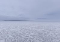 a picture of an overcast sky over a vast plain of snow with a large mountain in the distance